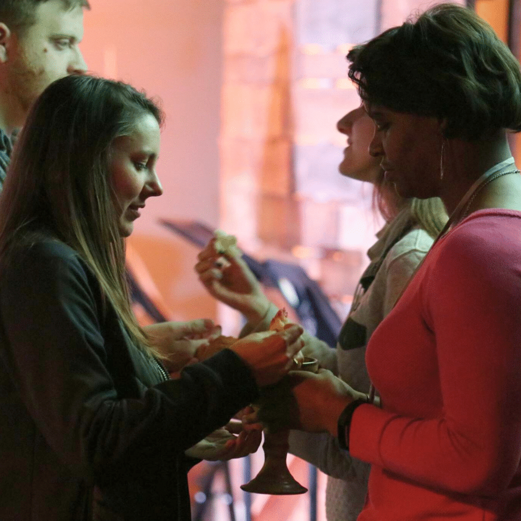A woman serving communion as a return to the sacraments and doing less.